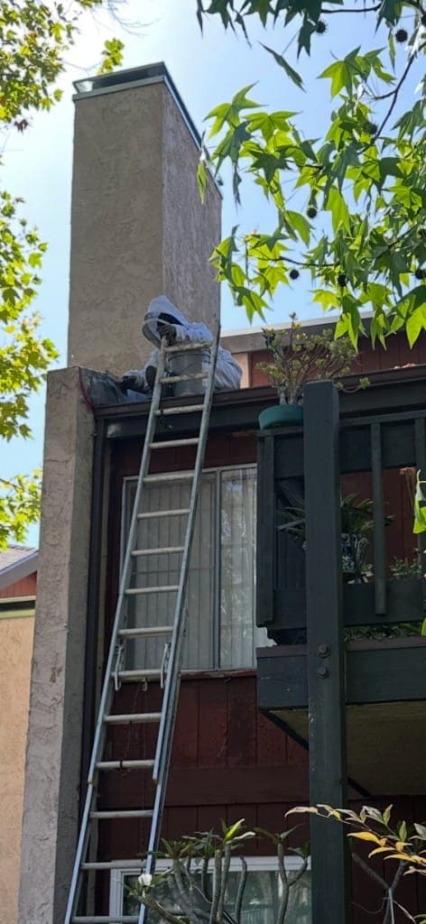 Raven technician in a full bee suit removing a hive from a chimney